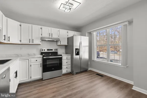 a kitchen with granite countertop a refrigerator stove top oven and sink