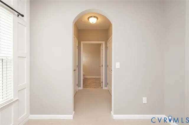 a view of a hallway with wooden floor and a small refrigerator