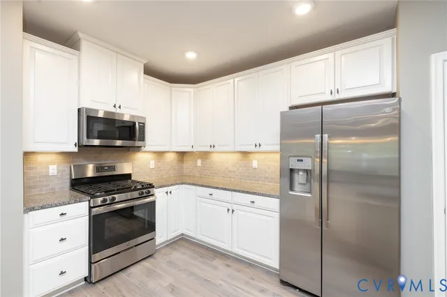a kitchen with white cabinets and stainless steel appliances