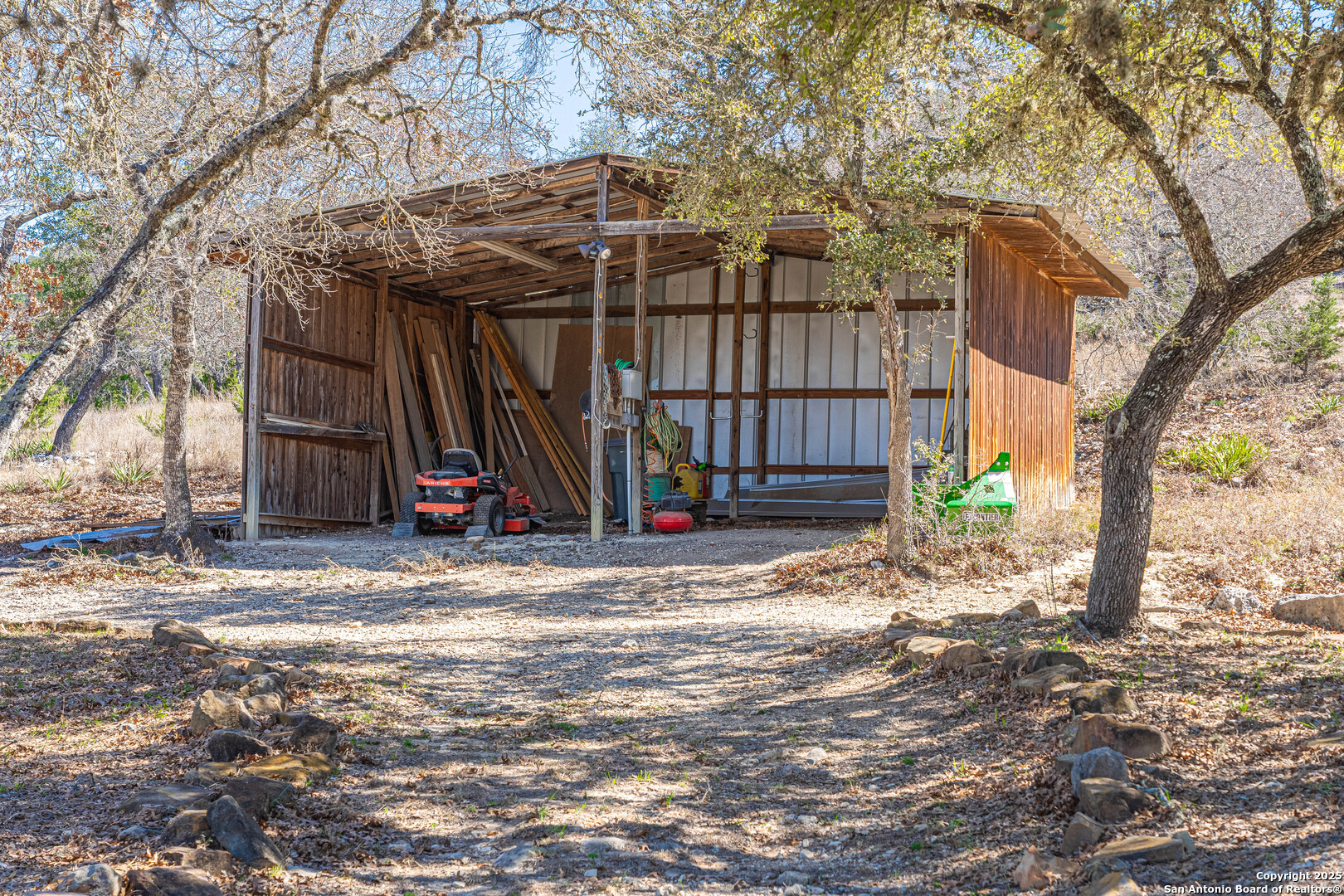 1839 Thanksgiving Road Utopia, TX 78884 - Photo 62 of 96 a view of a wooden house with a large tree and a yard