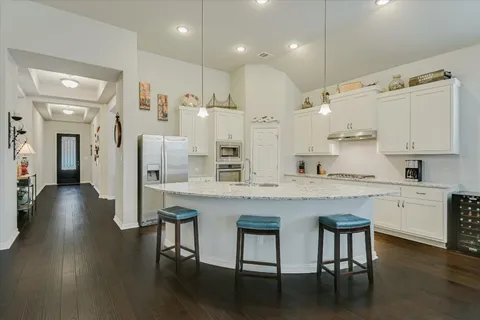 a kitchen with stainless steel appliances granite countertop a table chairs sink and cabinets