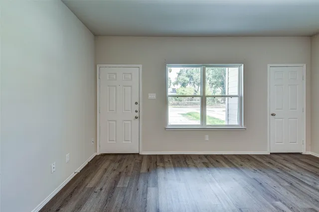 an empty room with wooden floor and windows
