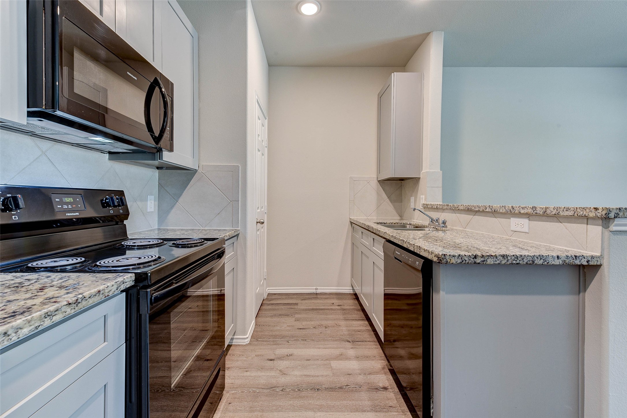 409 East Avenue G Conroe, TX 77301 - Photo 8 of 22 a kitchen with granite countertop a stove top oven and cabinetry