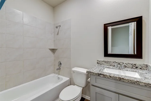 a bathroom with a granite countertop toilet a sink and bathtub