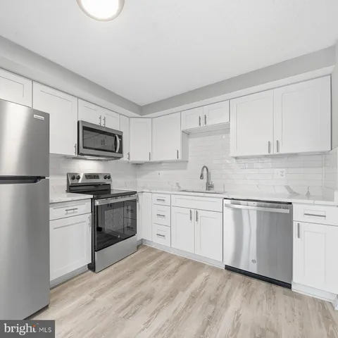 a kitchen with granite countertop white cabinets and stainless steel appliances