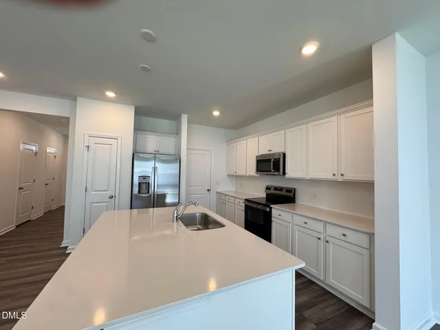 a kitchen with stainless steel appliances kitchen island sink refrigerator and cabinets