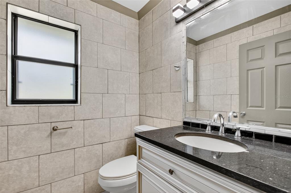 12903 112th Avenue Alachua, FL 32615 - Photo 59 of 95 a bathroom with a granite countertop sink toilet and mirror