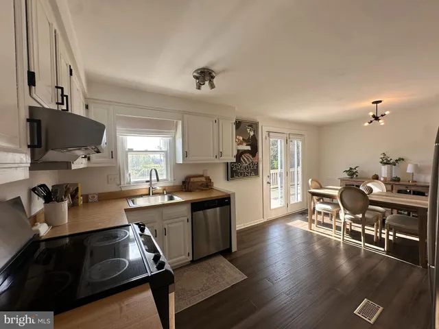 a kitchen with stainless steel appliances granite countertop a stove top oven a sink dishwasher and cabinets with wooden floor