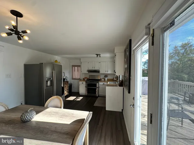 a kitchen with a refrigerator a stove and a dining table with wooden floor