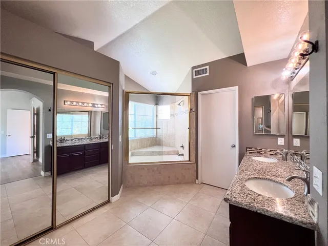 a bathroom with a granite countertop tub sink and mirror