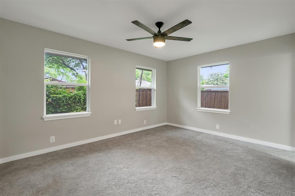 4815 Kelman Street Dallas, TX 75214 - Photo 22 of 37 Spacious interior room featuring light gray walls, gray carpet flooring, a modern ceiling fan with integrated lighting, and three windows offering natural light