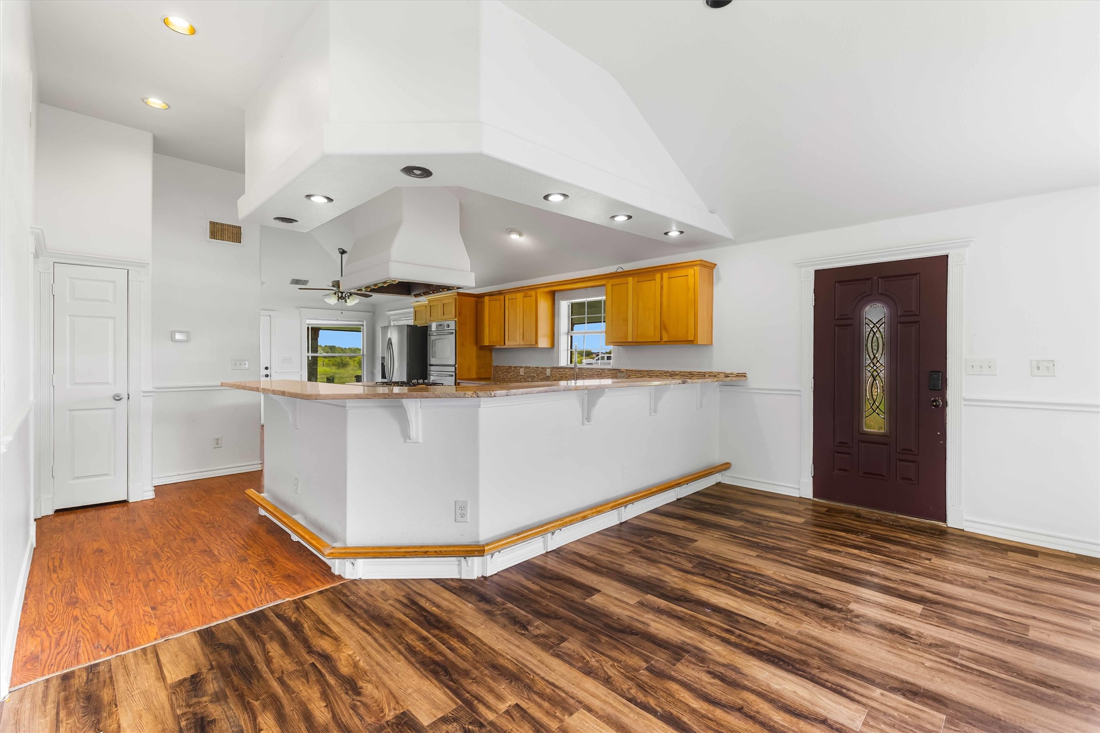 12212 Ballerstedt Road Elgin, TX 78621 - Photo 9 of 39 Kitchen with a peninsula, a kitchen bar, dark wood-type flooring, wood finish cabinets, and vaulted ceiling