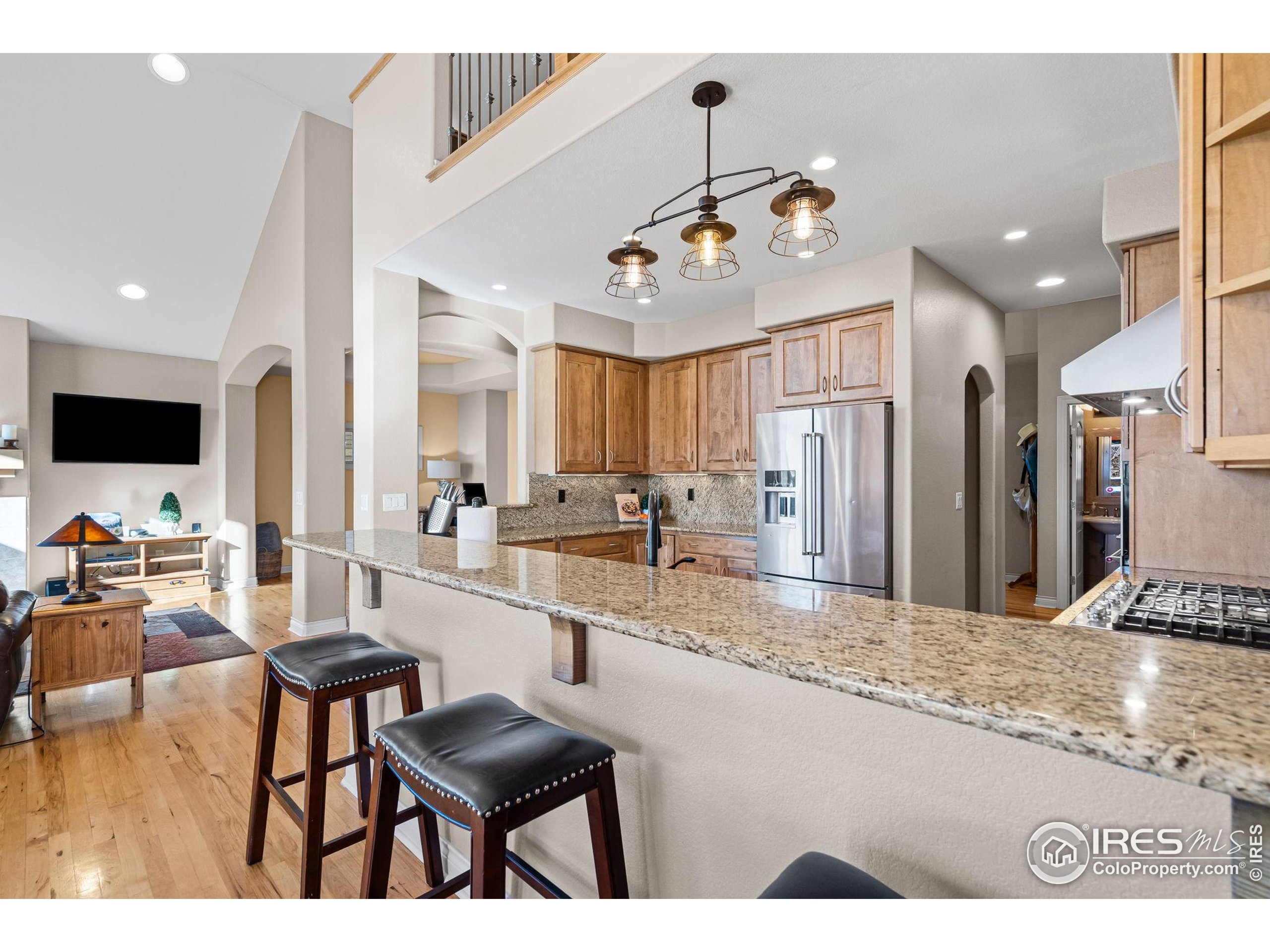 621 Roma Valley Drive Fort Collins, CO 80525 - Photo 13 of 50 a large kitchen with stainless steel appliances kitchen island granite countertop a table chairs in it and wooden floors