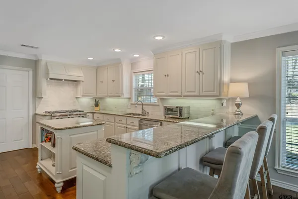 a kitchen with granite countertop a sink window and cabinets