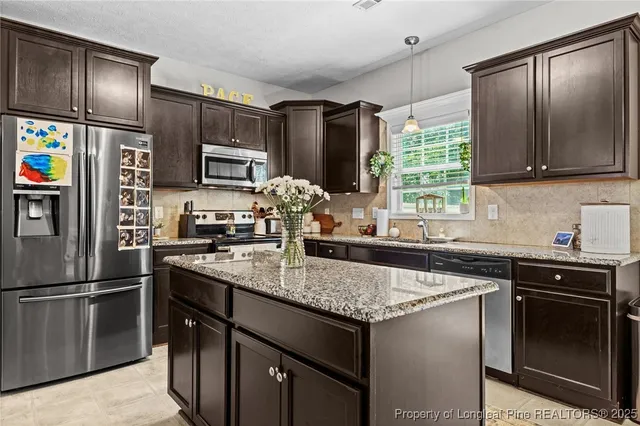 a kitchen with granite countertop a sink stove and refrigerator