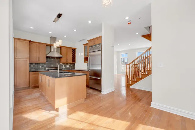 a kitchen with stainless steel appliances kitchen island granite countertop a refrigerator and a stove top oven