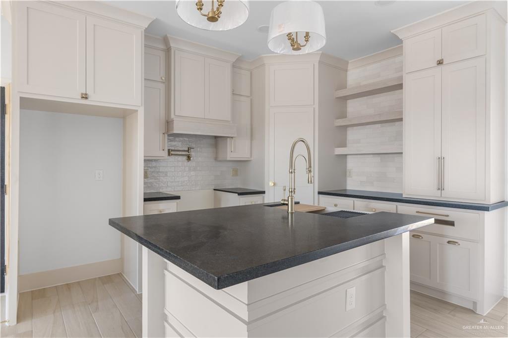 311 Other Road Rio Grande City, TX 78582 - Photo 4 of 16 Kitchen with a center island with sink, backsplash, light wood-style floors, open shelves, and pendant lighting