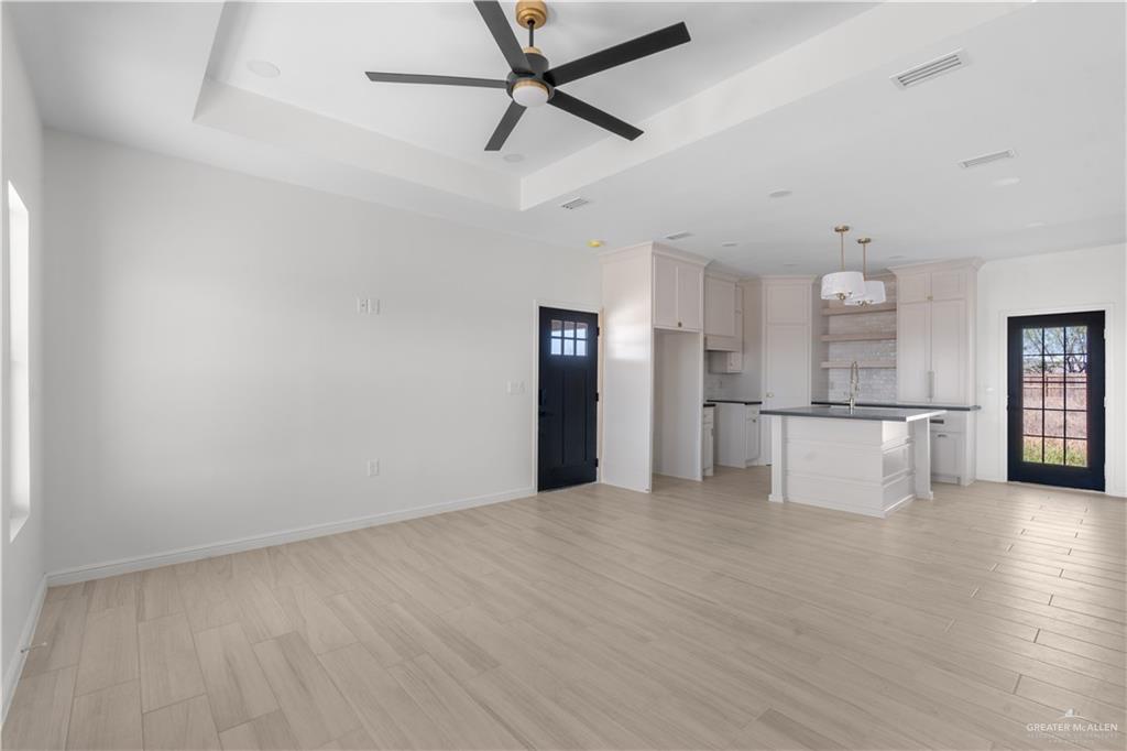 311 Other Road Rio Grande City, TX 78582 - Photo 7 of 16 Unfurnished living room with plenty of natural light, light wood-style floors, ceiling fan, and a tray ceiling