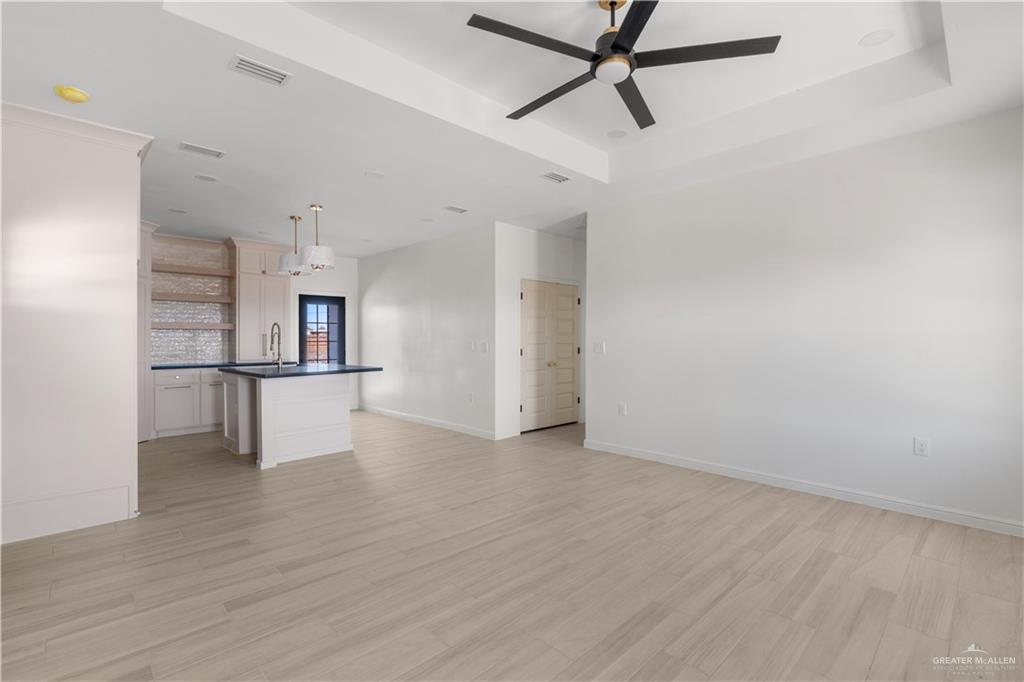 311 Other Road Rio Grande City, TX 78582 - Photo 8 of 16 Unfurnished living room featuring light wood-type flooring, ceiling fan, and a raised ceiling