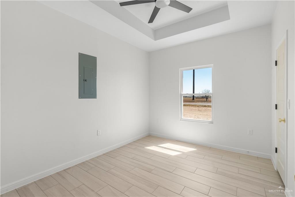 311 Other Road Rio Grande City, TX 78582 - Photo 9 of 16 Empty room with wood finish floors, electric panel, a tray ceiling, and ceiling fan