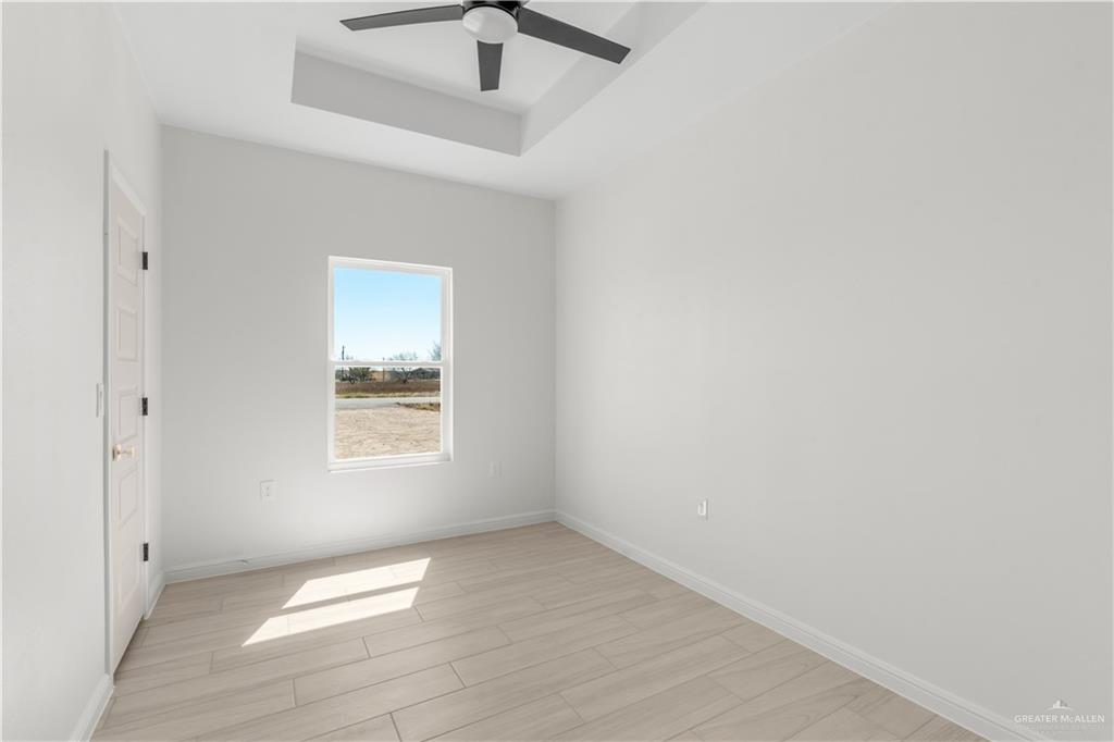 311 Other Road Rio Grande City, TX 78582 - Photo 10 of 16 Spare room with a tray ceiling, wood finish floors, and ceiling fan