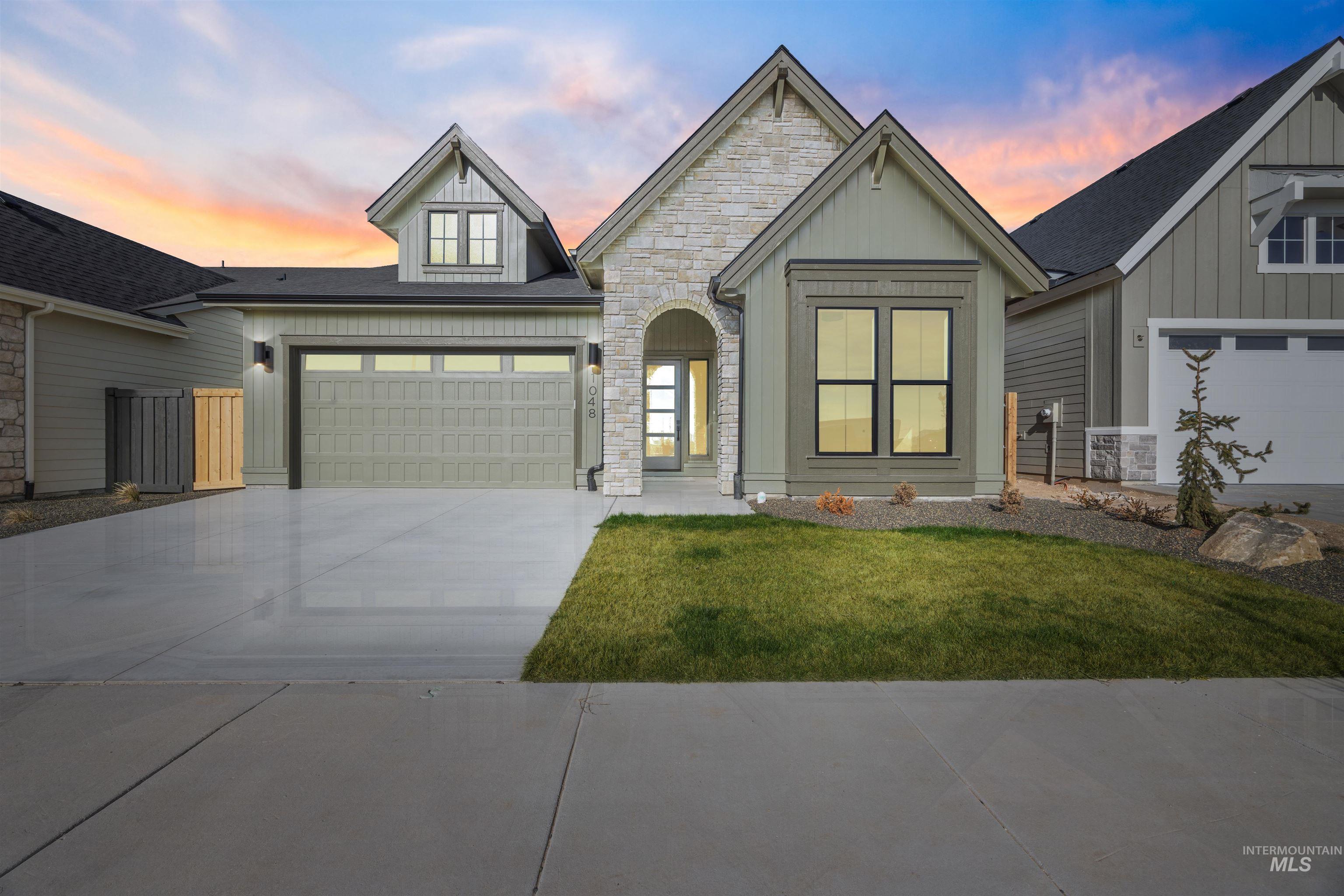 1048 East Escalation Street Meridian, ID 83642 - Photo 1 of 44 View of front of property with stone siding, a front yard, concrete driveway, and board and batten siding