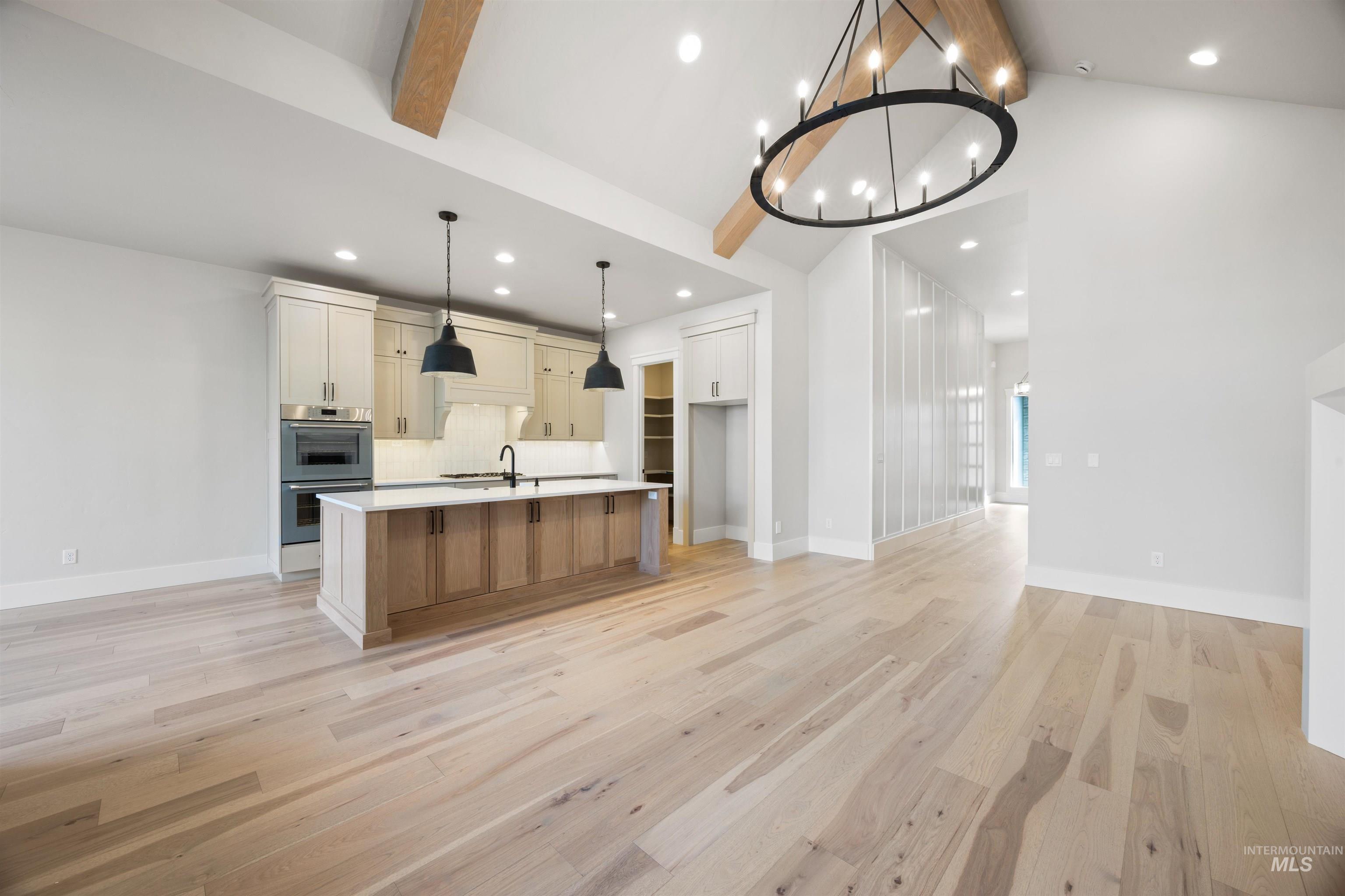1048 East Escalation Street Meridian, ID 83642 - Photo 12 of 44 Two tone kitchen with light wood-style floors, a center island with sink, dual tone cabinetry, stainless steel double oven, and a chandelier