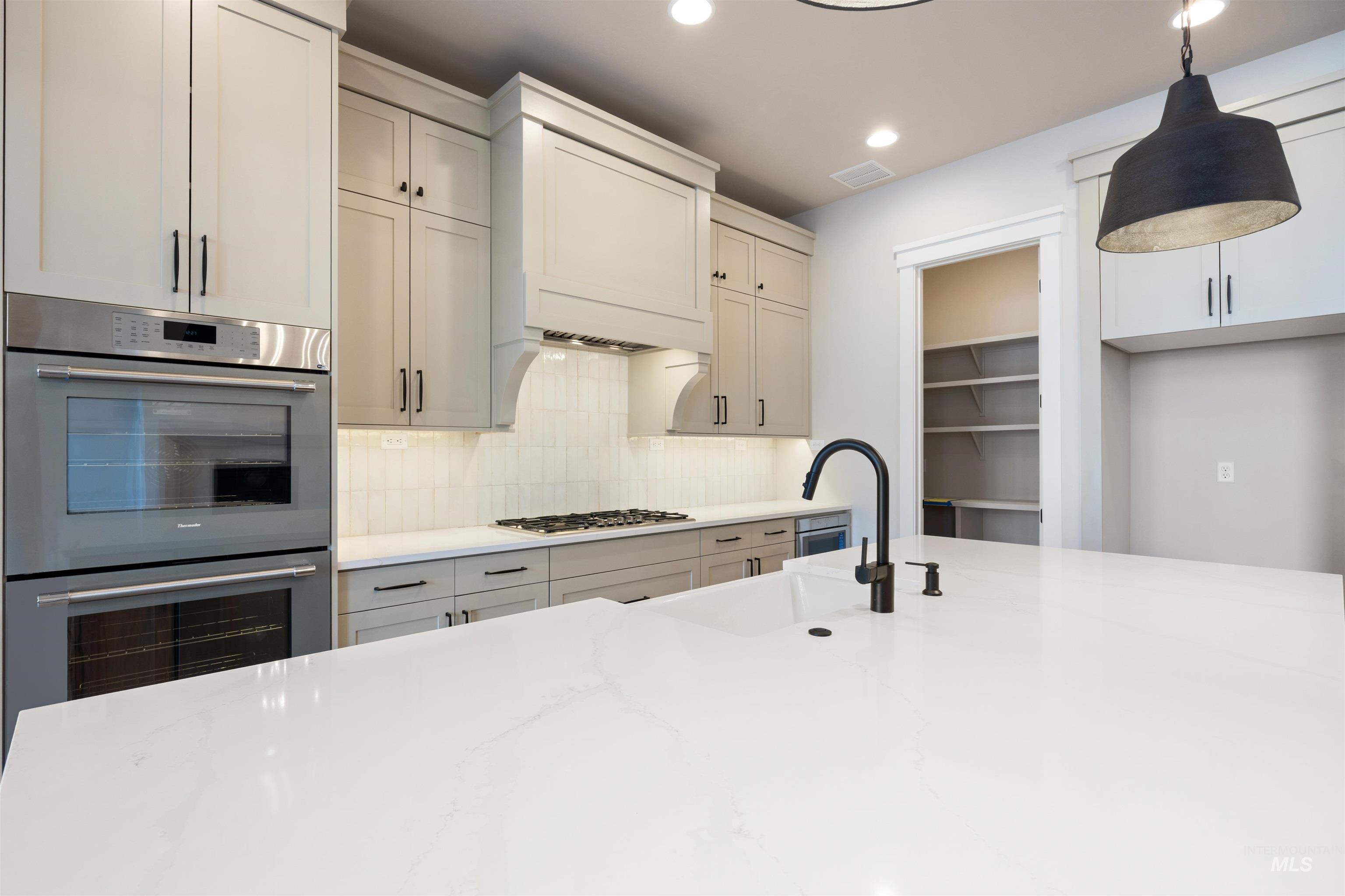 1048 East Escalation Street Meridian, ID 83642 - Photo 19 of 44 Kitchen with stainless steel appliances, decorative backsplash, light stone countertops, and decorative light fixtures