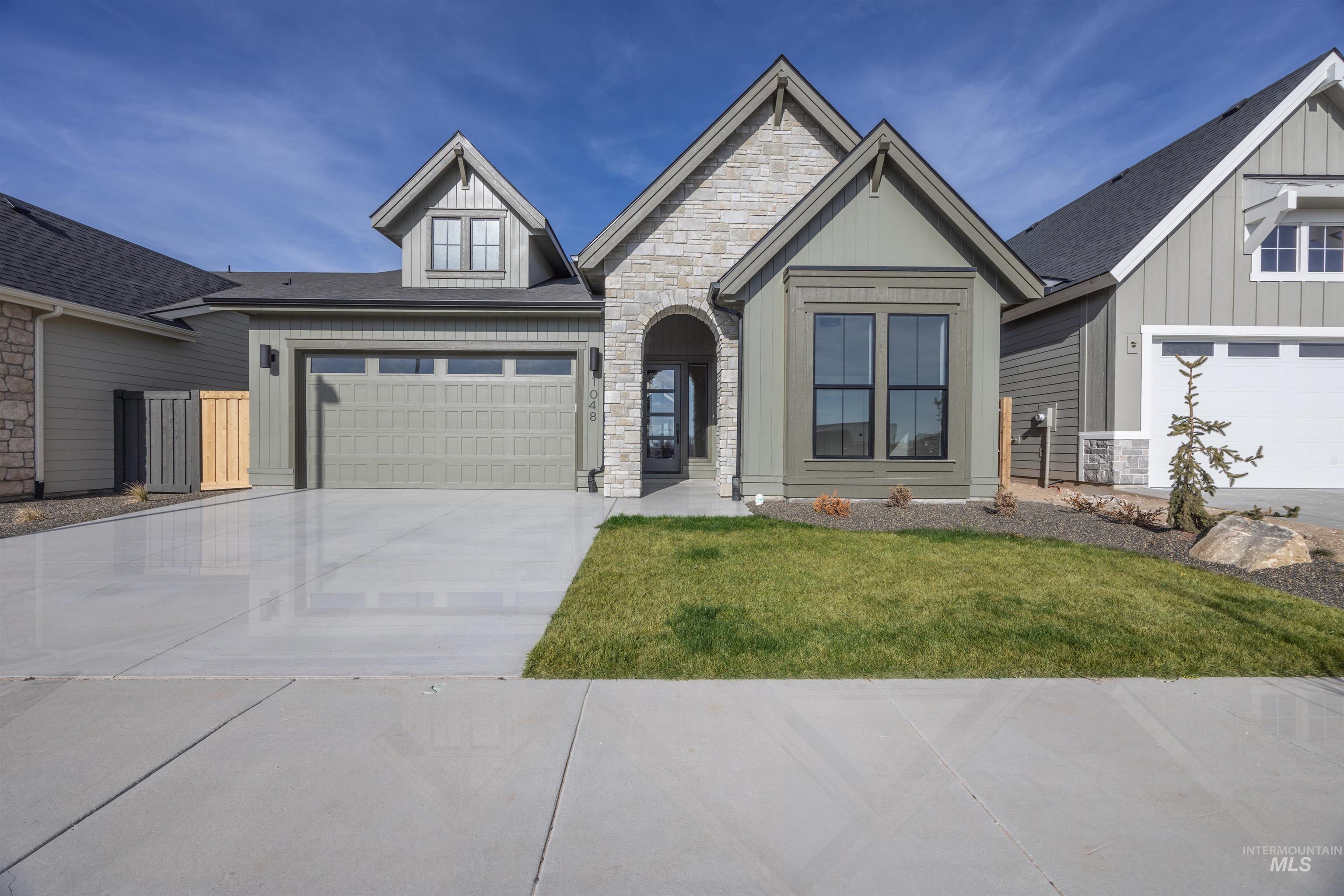 1048 East Escalation Street Meridian, ID 83642 - Photo 2 of 44 View of front facade featuring stone siding, a front lawn, concrete driveway, board and batten siding, and a shingled roof