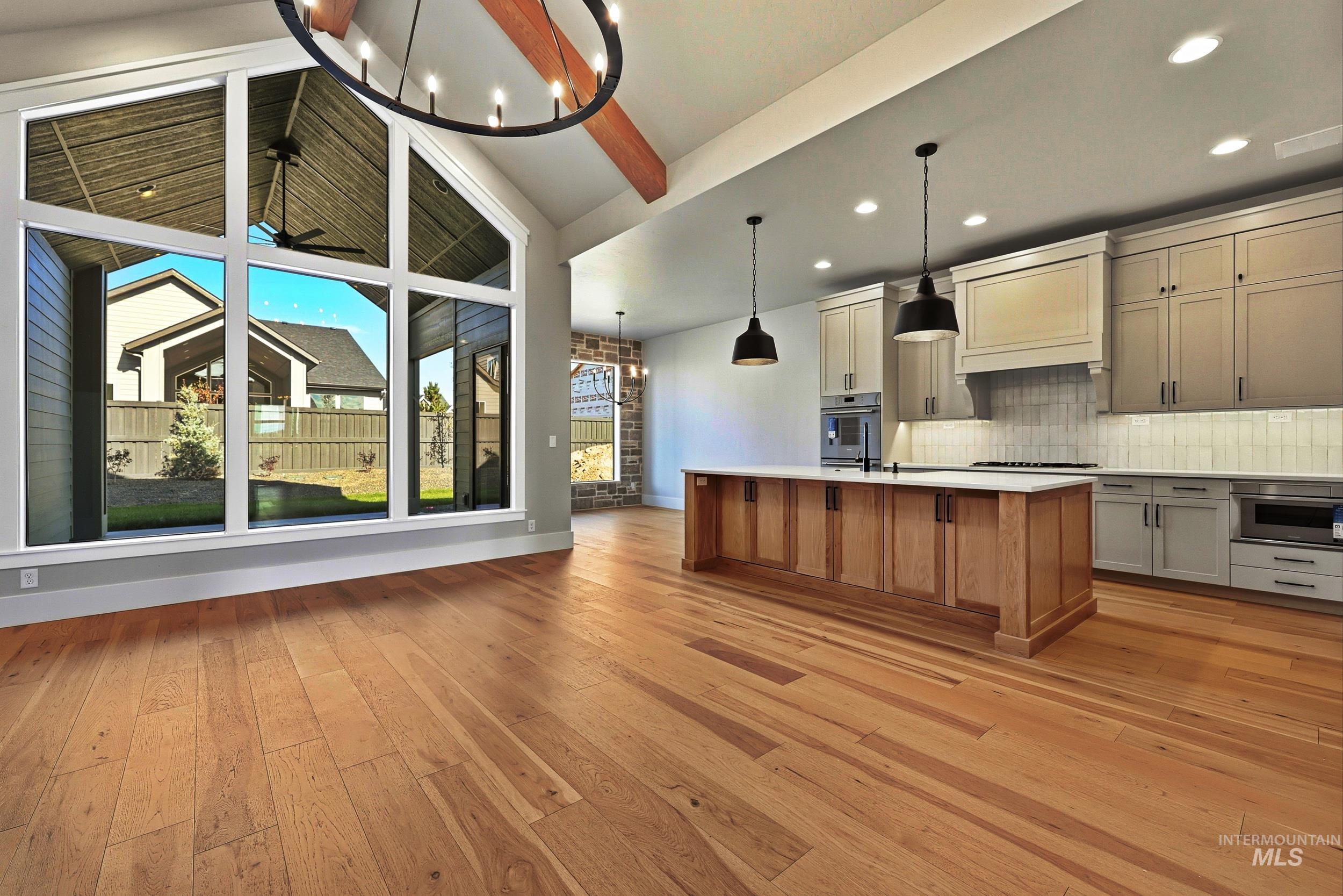 1048 East Escalation Street Meridian, ID 83642 - Photo 2 of 44 Kitchen featuring a chandelier, an island with sink, decorative light fixtures, and brown cabinetry