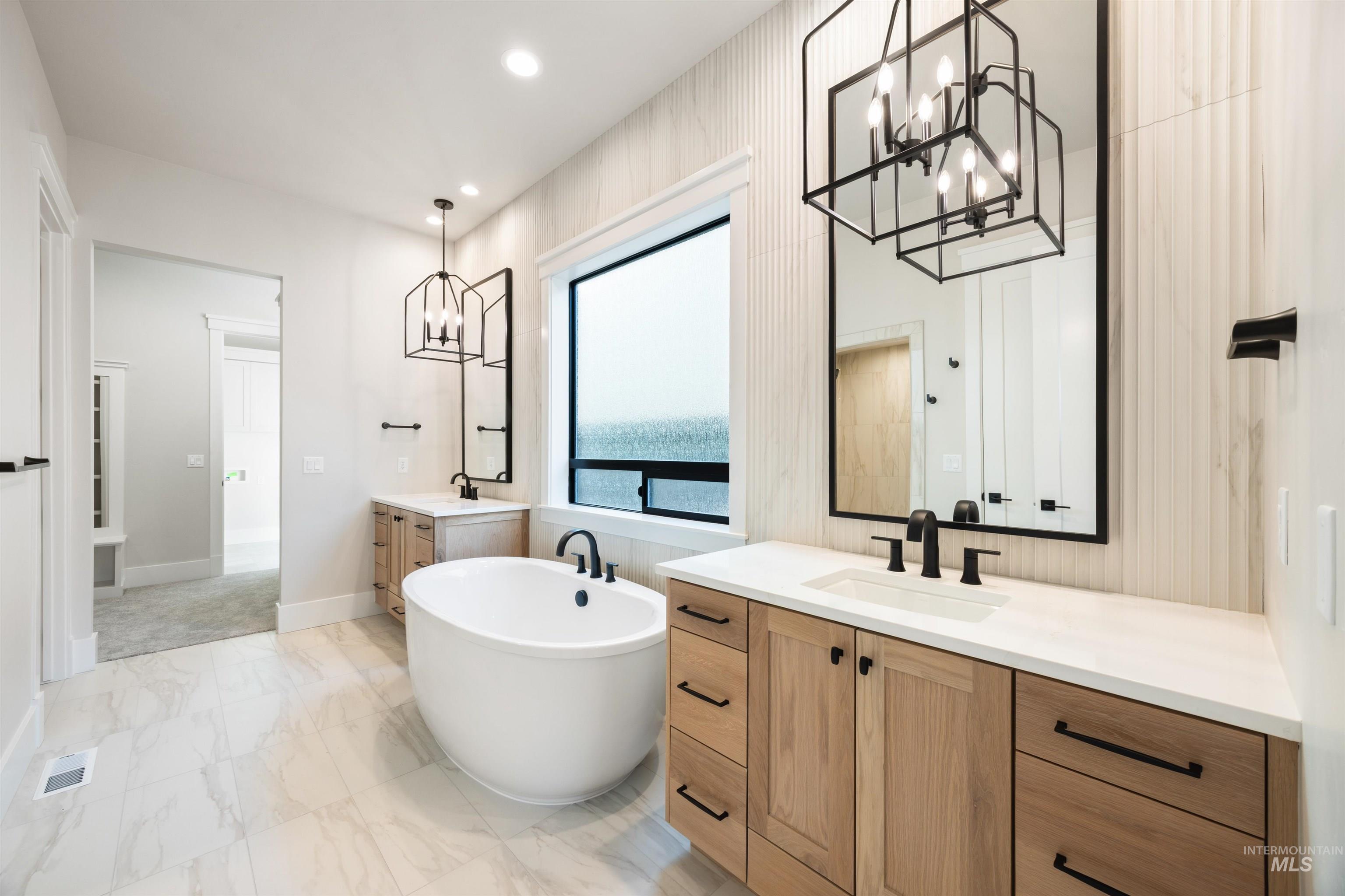 1048 East Escalation Street Meridian, ID 83642 - Photo 29 of 44 Bathroom with hanging lights, two vanities, a soaking tub, and light marble finish floors