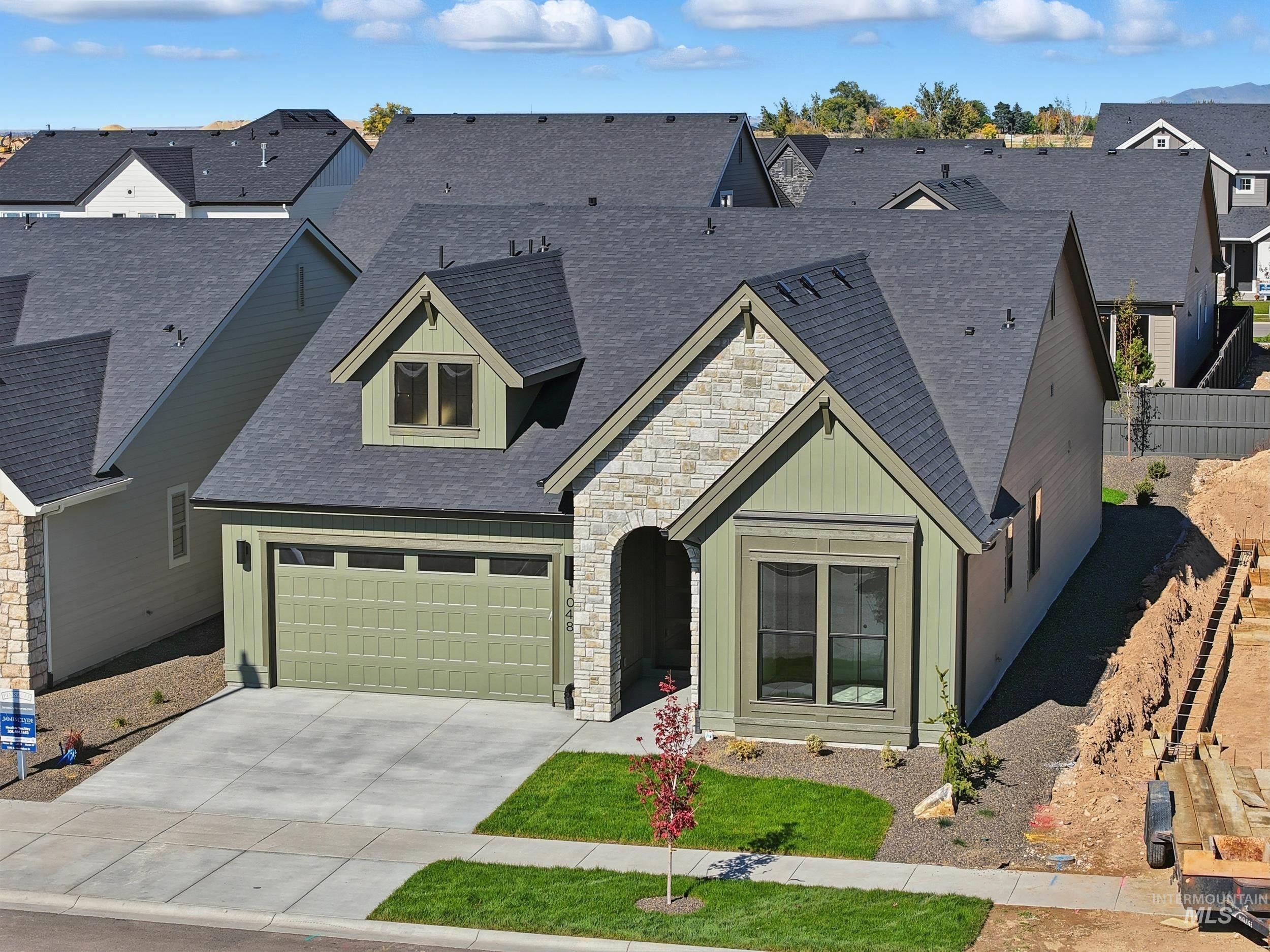 1048 East Escalation Street Meridian, ID 83642 - Photo 43 of 44 View of front of home with stone siding, a shingled roof, concrete driveway, a garage, and a residential view