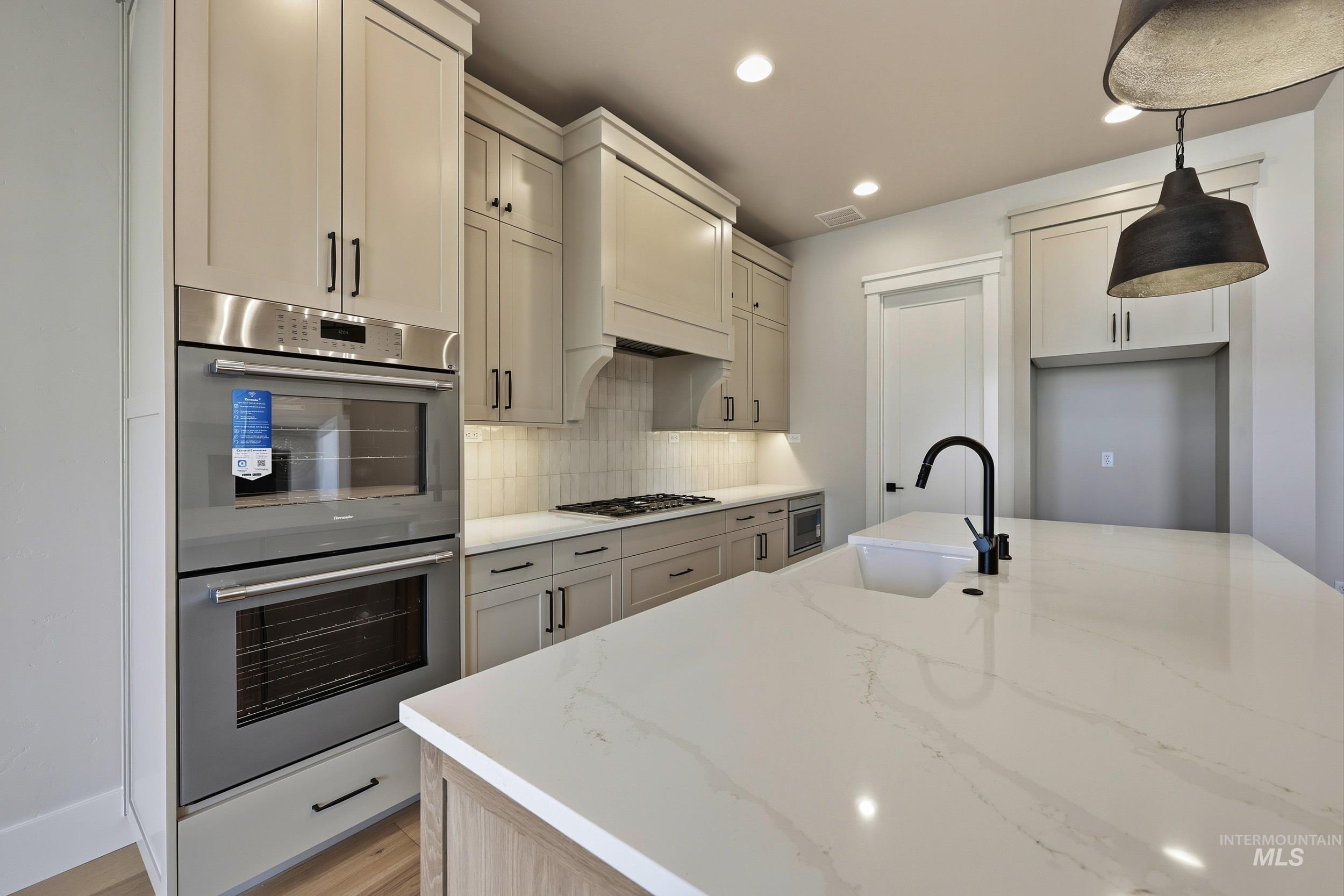 1048 East Escalation Street Meridian, ID 83642 - Photo 7 of 44 Kitchen with stainless steel appliances, light stone counters, hanging light fixtures, tasteful backsplash, and recessed lighting