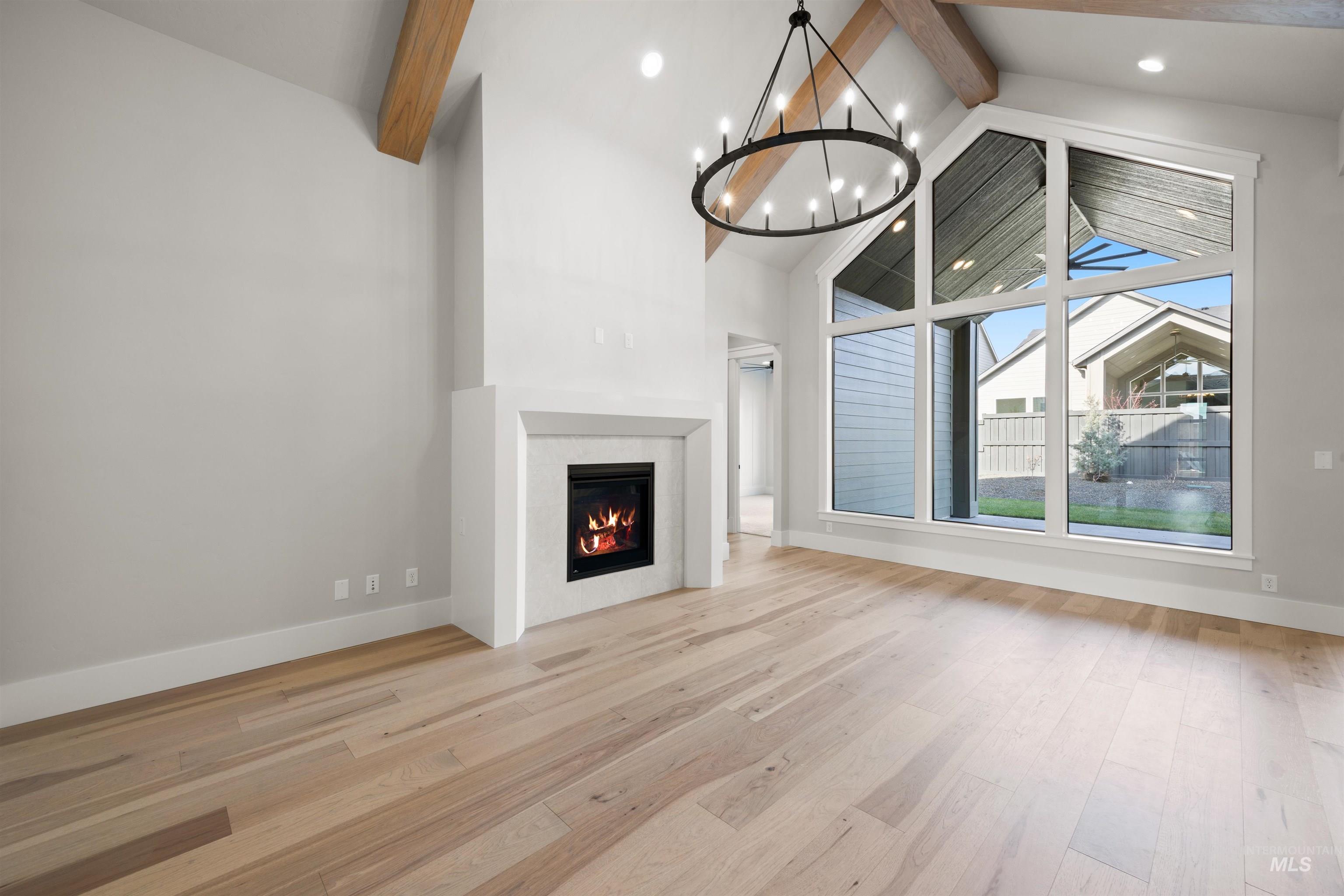 1048 East Escalation Street Meridian, ID 83642 - Photo 10 of 44 Unfurnished living room with a warm lit fireplace, light wood-style floors, and hanging lights