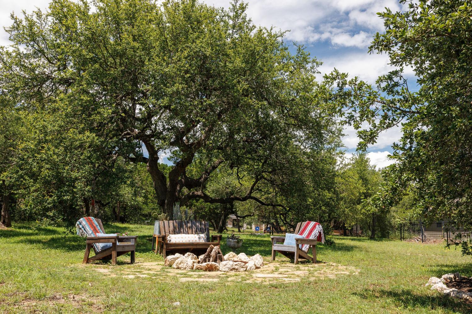 1135 Blue Ridge Drive Dripping Springs, TX 78620 - Photo 2 of 36 An inviting outdoor oasis, perfect for enjoying quiet evenings under a vast, mature tree.