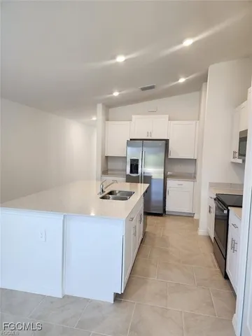 a kitchen with kitchen island granite countertop a sink and refrigerator