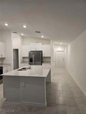a large white kitchen with a large counter top stainless steel appliances and cabinets