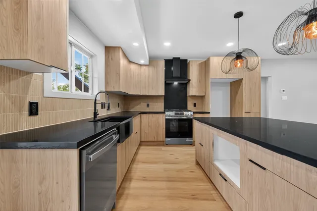 a kitchen with granite countertop a sink a counter top space a stove and cabinets