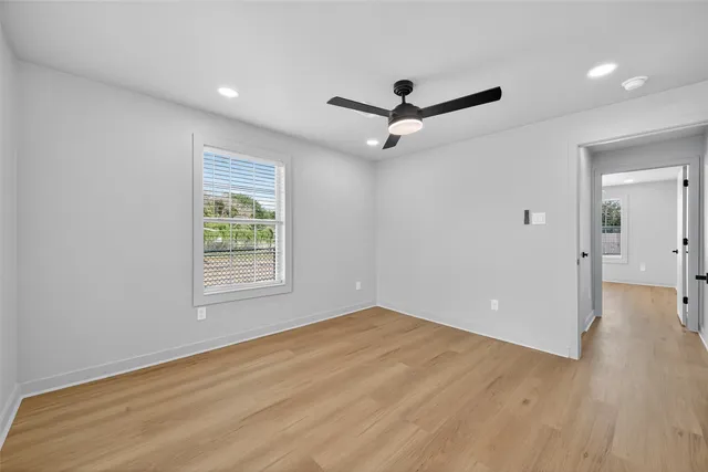 a view of empty room with wooden floor and fan