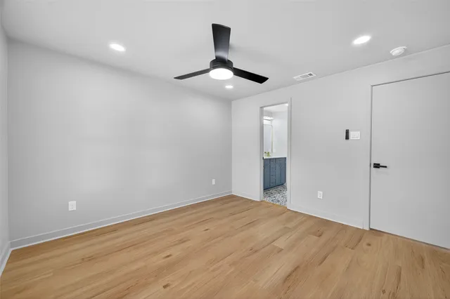 a view of an empty room and chandelier fan and kitchen view