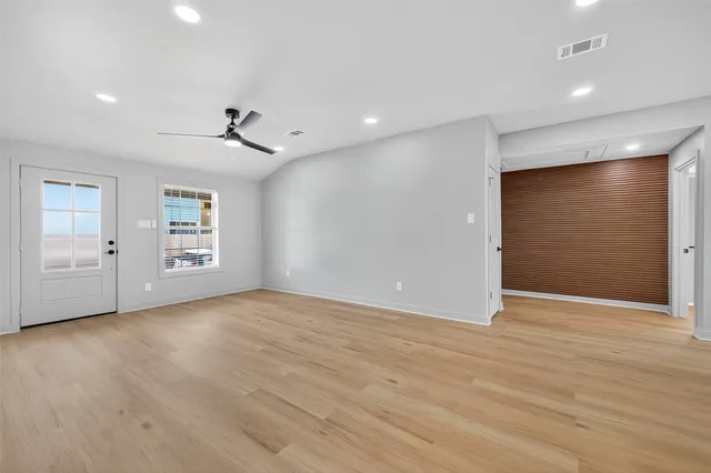 a view of an empty room with a window and wooden floor