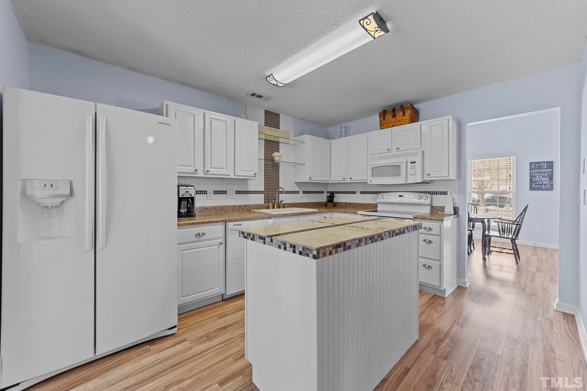 5022 Silhouette Drive Durham, NC 27713 - Photo 12 of 26 a kitchen with kitchen island granite countertop a sink cabinets and wooden floor
