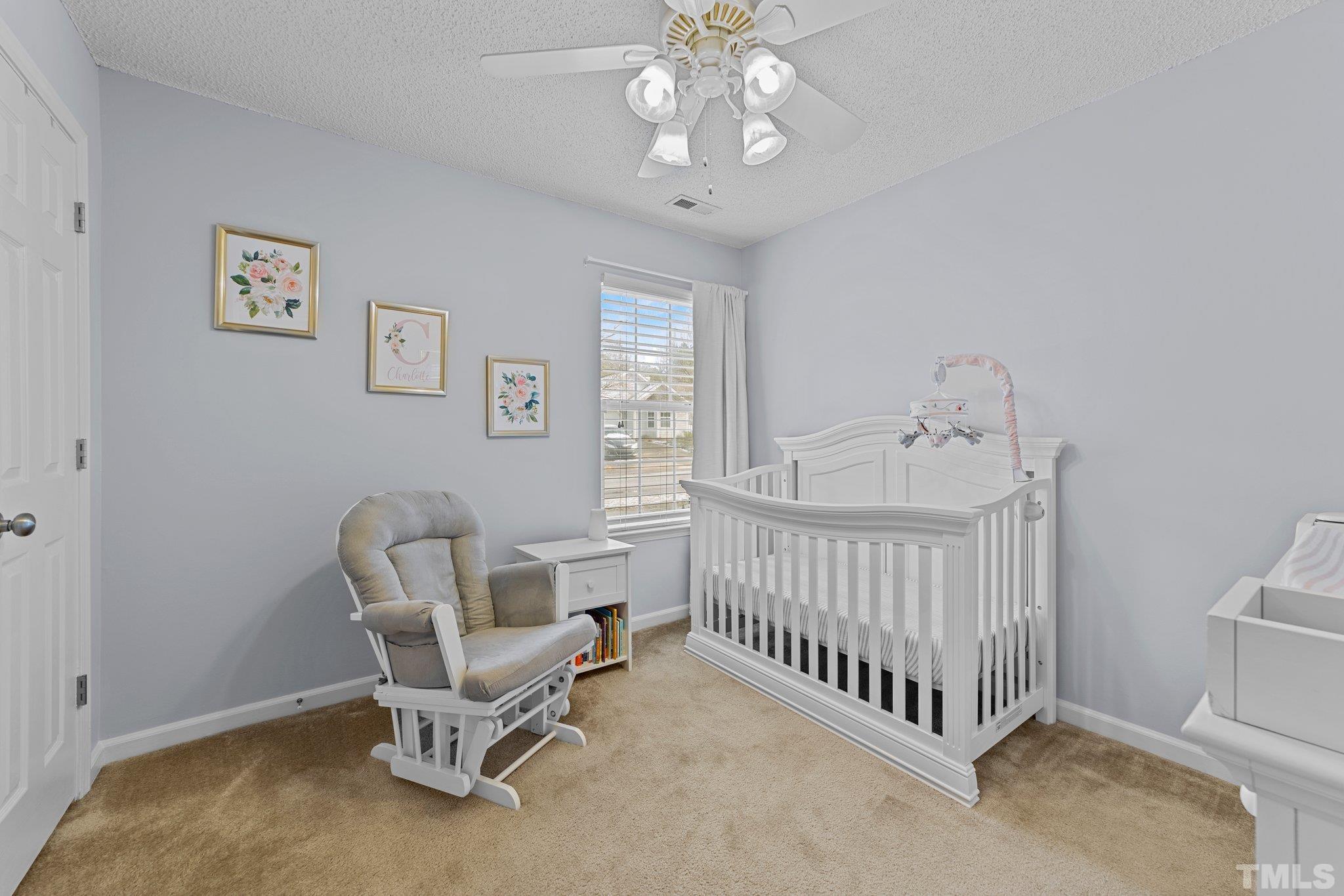 5022 Silhouette Drive Durham, NC 27713 - Photo 17 of 26 a living room with a baby crib furniture a window and a chandelier