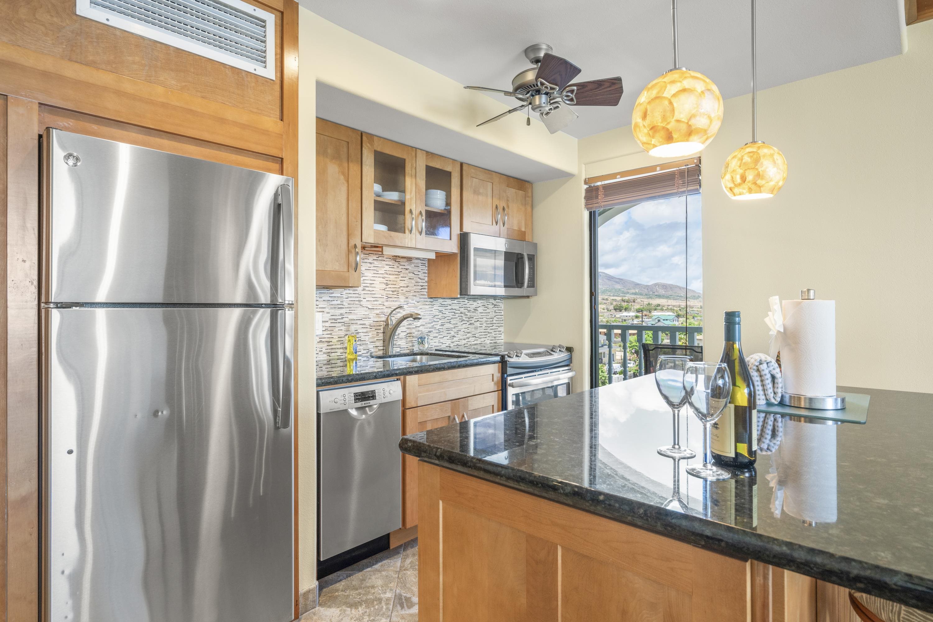 475 Front Street, Unit 601 Lahaina, HI 96761 - Photo 11 of 24 a kitchen with stainless steel appliances granite countertop a refrigerator a stove and a sink with wooden floor