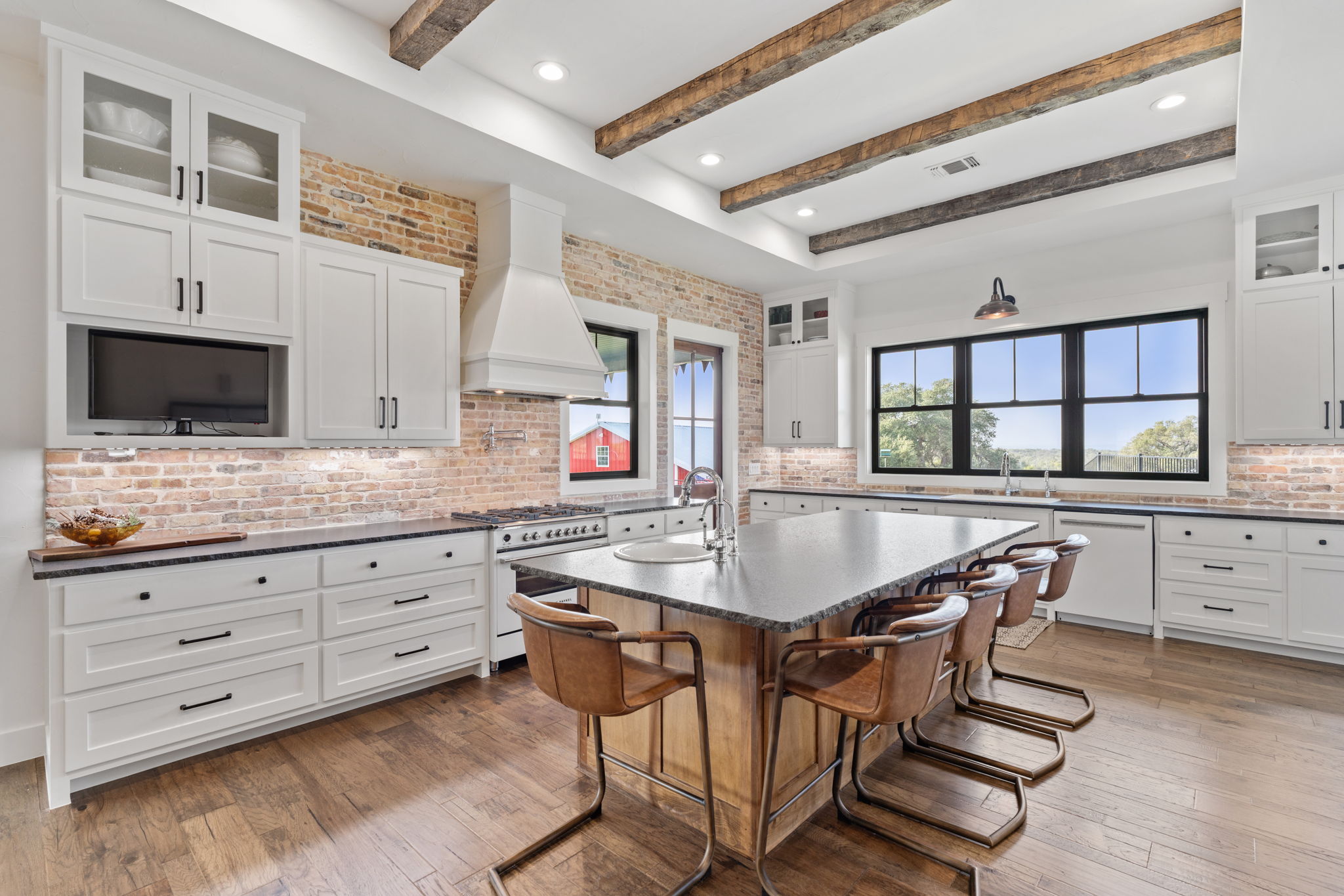 452 Southwick Ranch Road Johnson City, TX 78636 - Photo 12 of 40 Exposed wood beams and brick accents complement a modern kitchen with a large island and ample natural light.