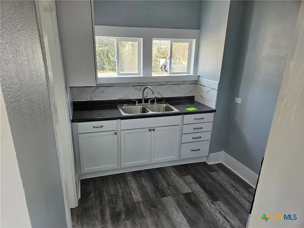 a kitchen with granite countertop a sink and a white cabinets