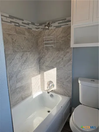 a white toilet sitting next to a window in a bathroom