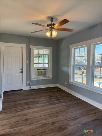 a view of an empty room with wooden floor and a window