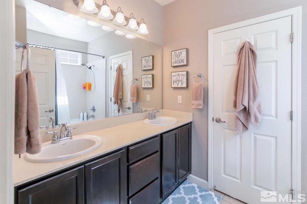 11057 Colton Drive Reno, NV 89521 - Photo 17 of 22 a bathroom with a double vanity sink a mirror and a shower
