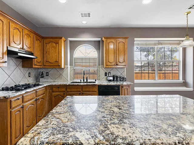 a kitchen with stainless steel appliances granite countertop a stove a sink and a microwave